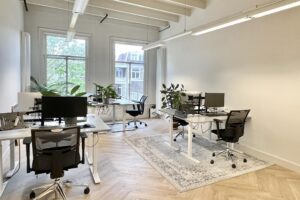 Licht en modern kantoor aan de Paulus Potterstraat met bureaus, bureaustoelen, computers en groene planten.